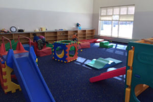 Durable shock absorbing carpet system with slides and children playing in the background.