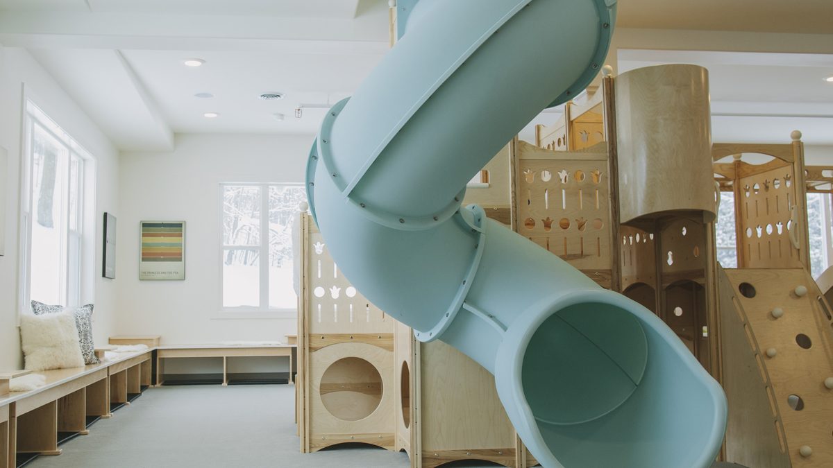 Safe Landings carpet system that is safe kids flooring and wood play ground with blue slide and rock wall.