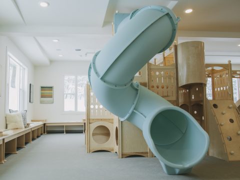 Safe Landings carpet system that is safe kids flooring and wood play ground with blue slide and rock wall.