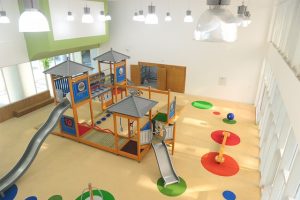 Long lasting indoor playground surfacing with custom cut sheet vinyl circles and an indoor playground with multiple slides. This installation meets ASTM F1292 standards.