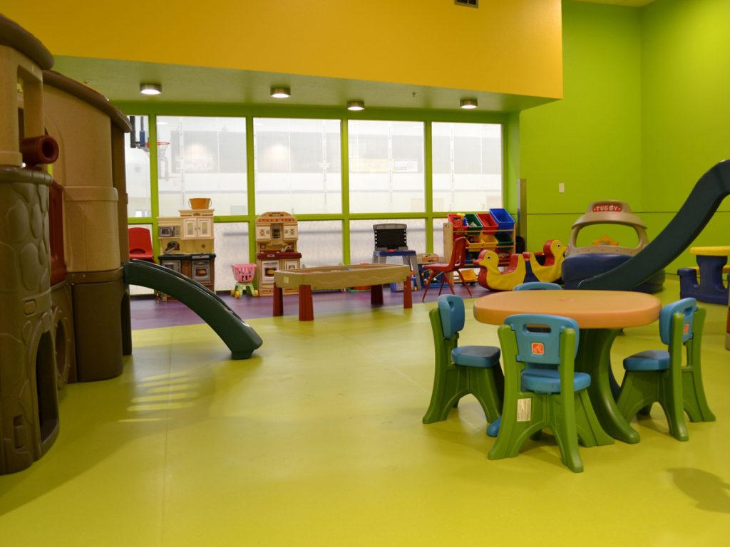 Green and purple sheet vinyl safety flooring for day cares with multiple play structure including two slides.