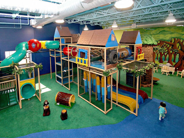 Children playing on SafeLandings Shock Absorbing Carpet System on a two story jungle gym. The carpet is a custom print with green and blue sections.