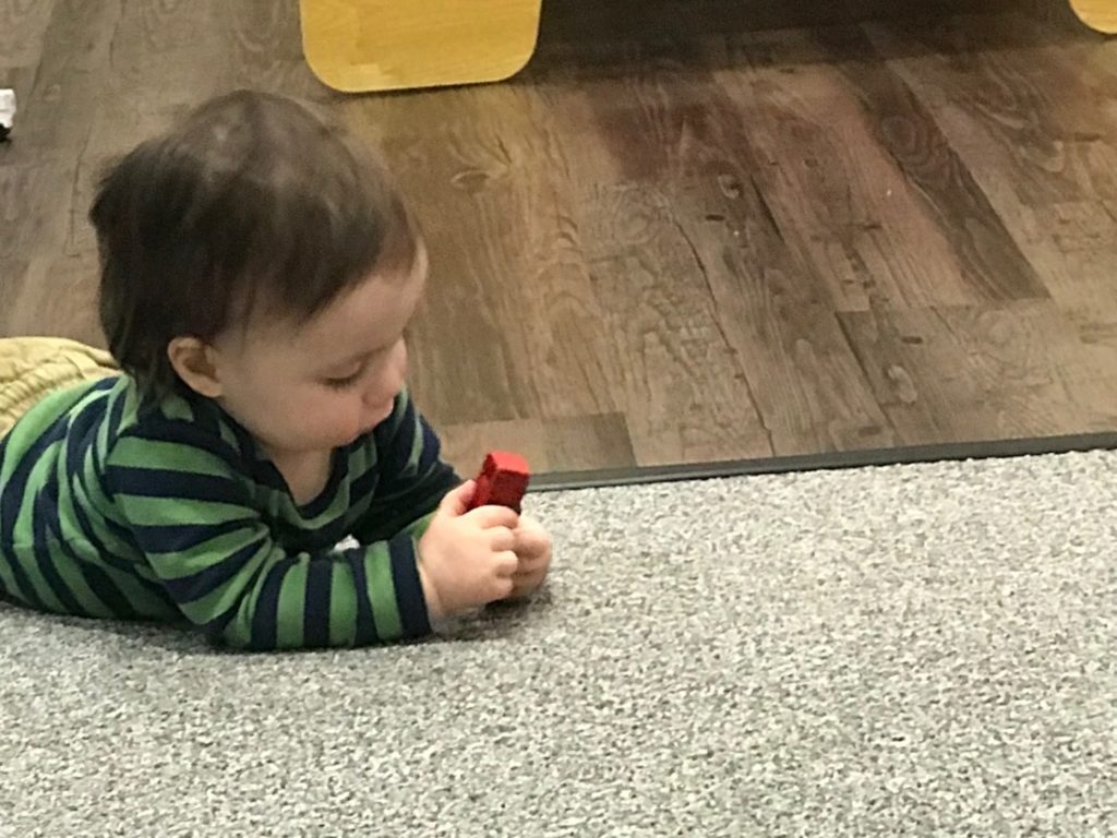 Toddler playing with red block on SafeLandings SafetyRug.