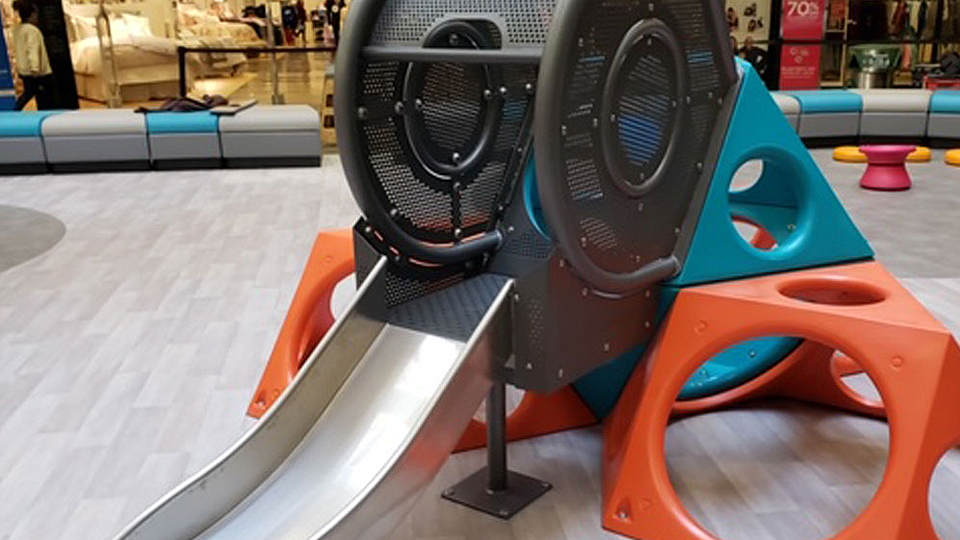 Indoor mall playground with safe flooring and slide with covered in circle and triangle shapes.